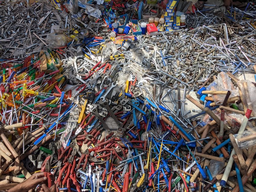 Imagem de uma pilha de ferramentas de diversos tipos e cores em um ambiente de descarte ou estoque.