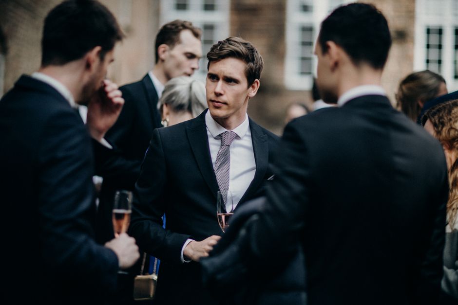 Homem em traje formal participando de uma conversa em um evento de negócios ao ar livre.