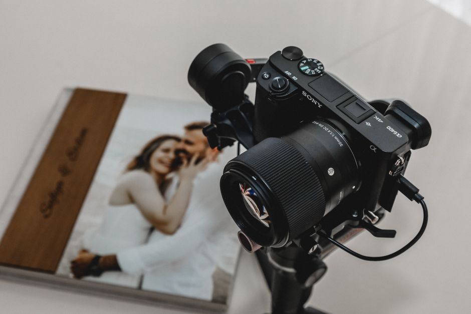 Câmera fotográfica apontada para um álbum de fotos com uma imagem de um casal sorridente, explorando o tema de fotografia e memórias.
