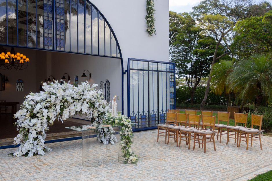Espaço ao ar livre preparado para cerimônia de casamento, decorado com flores brancas e cadeiras para convidados, com vista para a natureza.