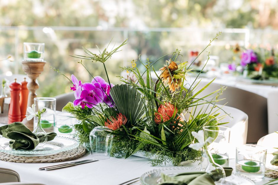 Arranjo de flores vibrantes decorando uma mesa de celebração ao ar livre.