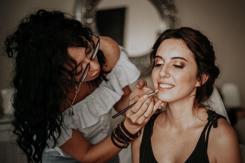 Mulher recebendo maquiagem profissional para um ensaio de fotos ou ocasião especial, com aparência de preparação e beleza.