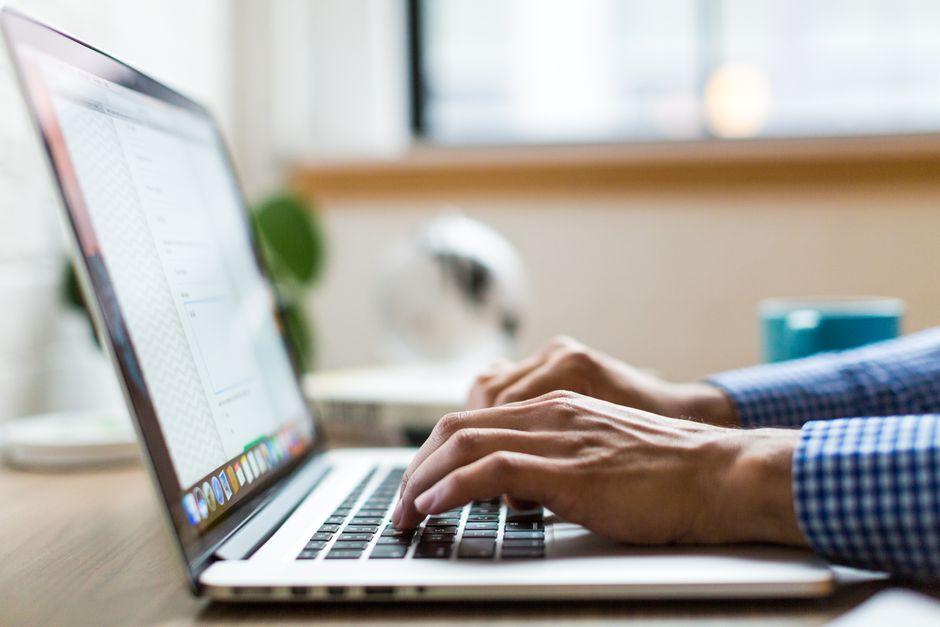 Pessoa trabalhando em um laptop em um ambiente de escritório, focada em suas tarefas.