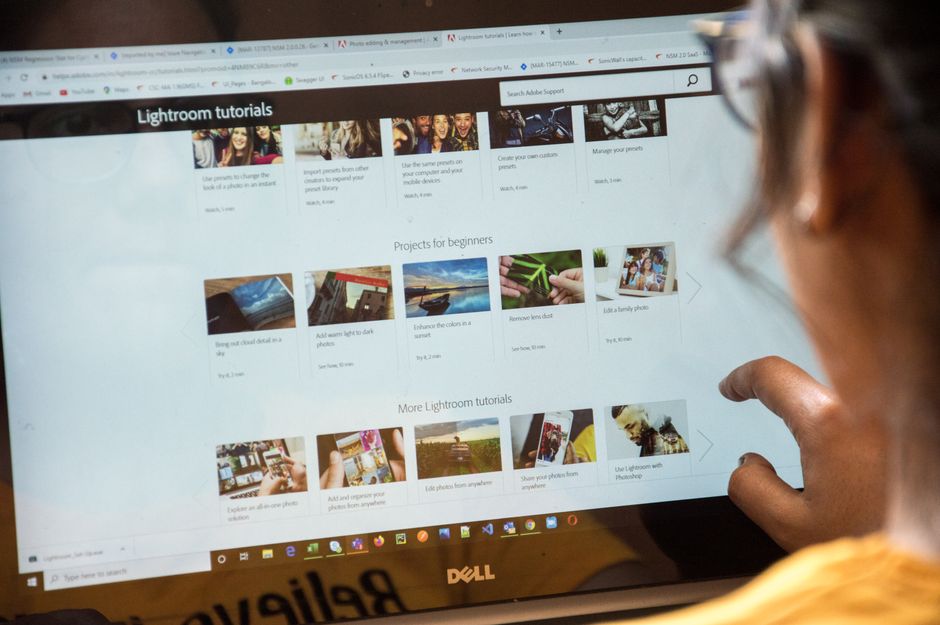 Pessoa navegando em tutoriais de Lightroom em um computador, demonstrando aprendizado de edição de fotos.