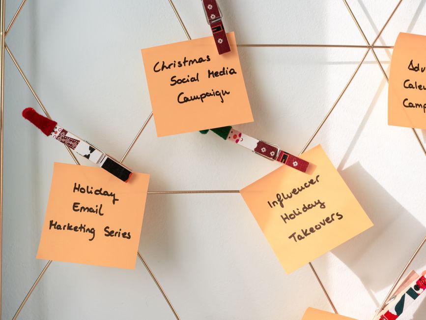 Quadro com notas adesivas relacionadas a estratégias de marketing e campanhas de mídias sociais, com elásticos decorativos prendendo as notas na parede.