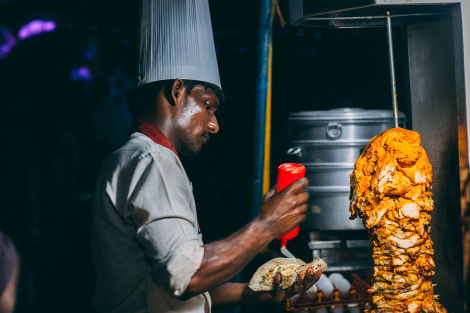 Chef preparando comida em um food truck ou barraca de rua, ilustrando a gastronomia de rua e cultura culinária.
