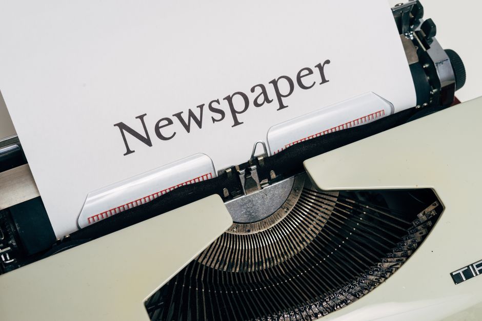 Imagem de uma máquina de escrever com a palavra 'Newspaper', representando o conceito de jornalismo e comunicação impressa.
