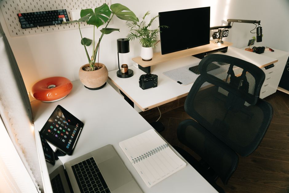 Imagem de um escritório organizado com tecnologia e plantas, ideal para artigos sobre produtividade e ergonomia no ambiente de trabalho.