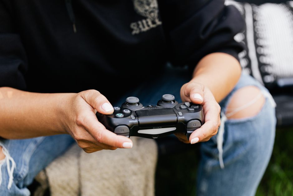 Pessoa jogando videogame com controle em um ambiente descontraído ao ar livre.