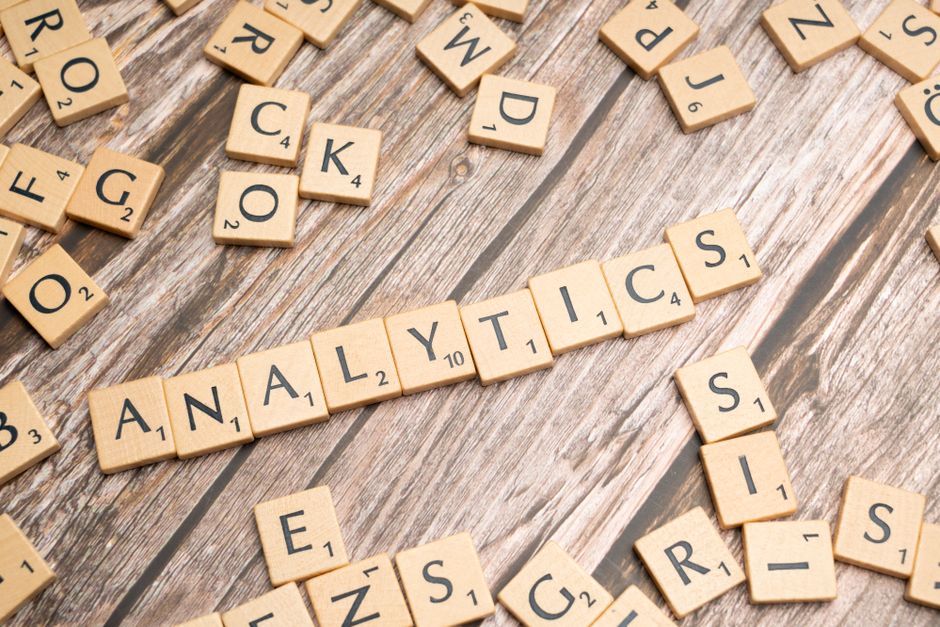 Imagem com peças de dominó formando a palavra 'ANALYTICS', representando análise de dados e inteligência de negócios.