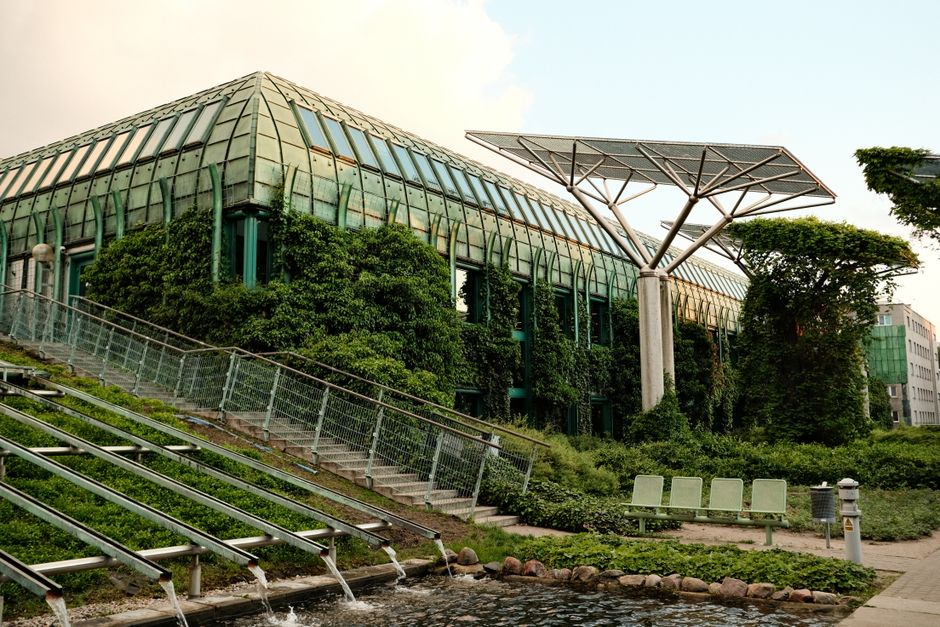 Edifício sustentável com uma estrutura moderna, integrado à natureza e equipado com painéis solares, ideal para artigos sobre inovação em arquitetura ecológica.
