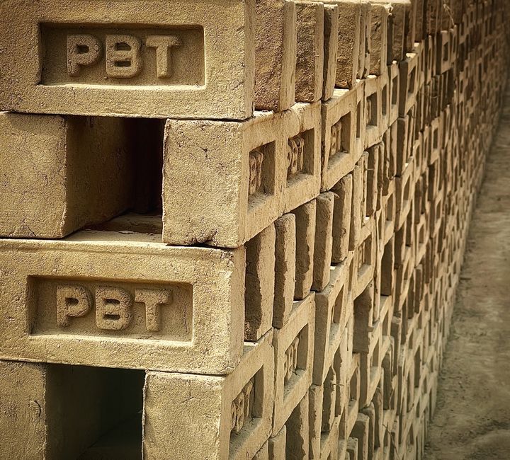 Imagem de uma pilha de blocos de construção de cimento com a marca PET, simbolizando sustentabilidade e uso de materiais reciclados na construção civil.