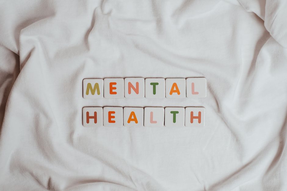 Imagem com blocos de letras formando a frase 'Saúde Mental', sobre um tecido branco, destacando a importância do bem-estar psicológico.