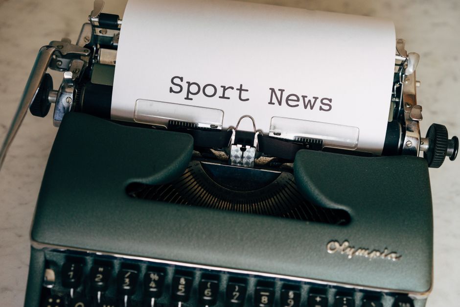 Máquina de escrever antiga com uma folha de papel contendo o texto 'Sport News', simbolizando notícias esportivas tradicionais e jornalismo clássico.