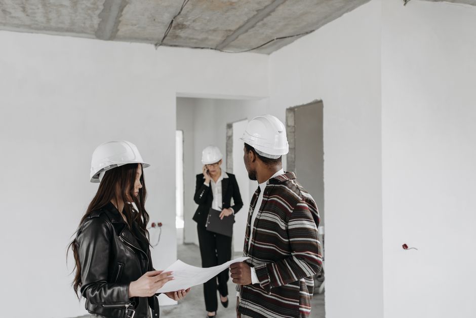 Engenheiros e profissionais de arquitetura discutindo planos em uma obra em fase de construção ou reforma.