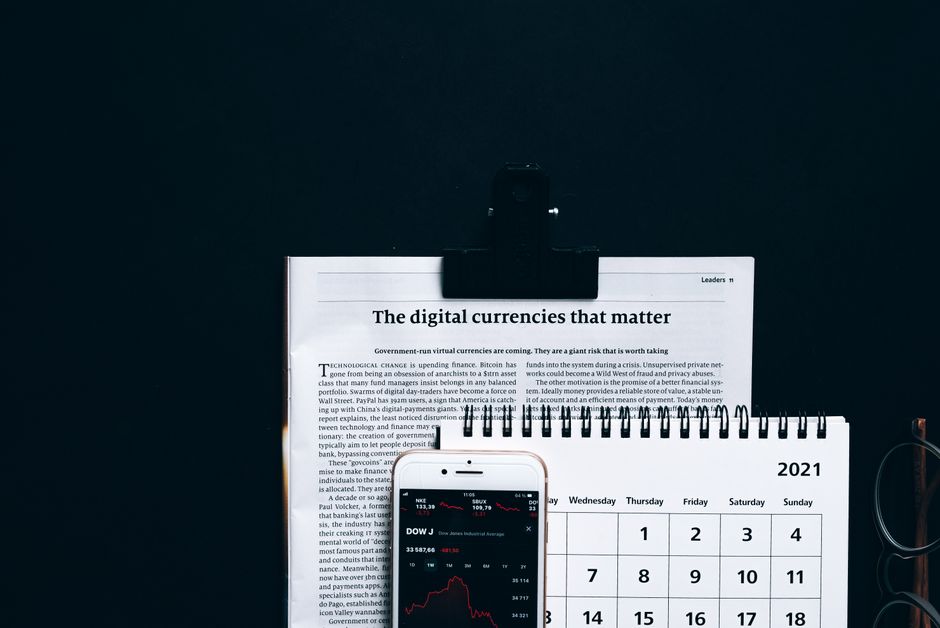 Imagem de um escritório com calendário, relatório financeiro e telefone exibindo dados de mercado, relacionada a temas de economia digital e gestão financeira.