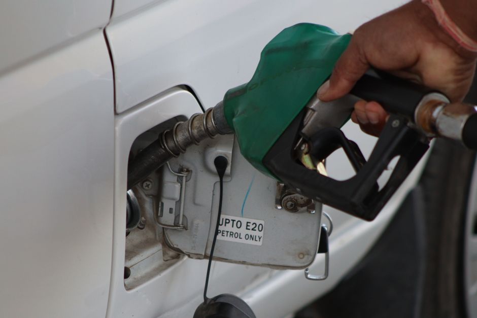 Pessoa abastecendo um carro com combustível em um posto de gasolina, focando na ação de reabastecimento de veículos.