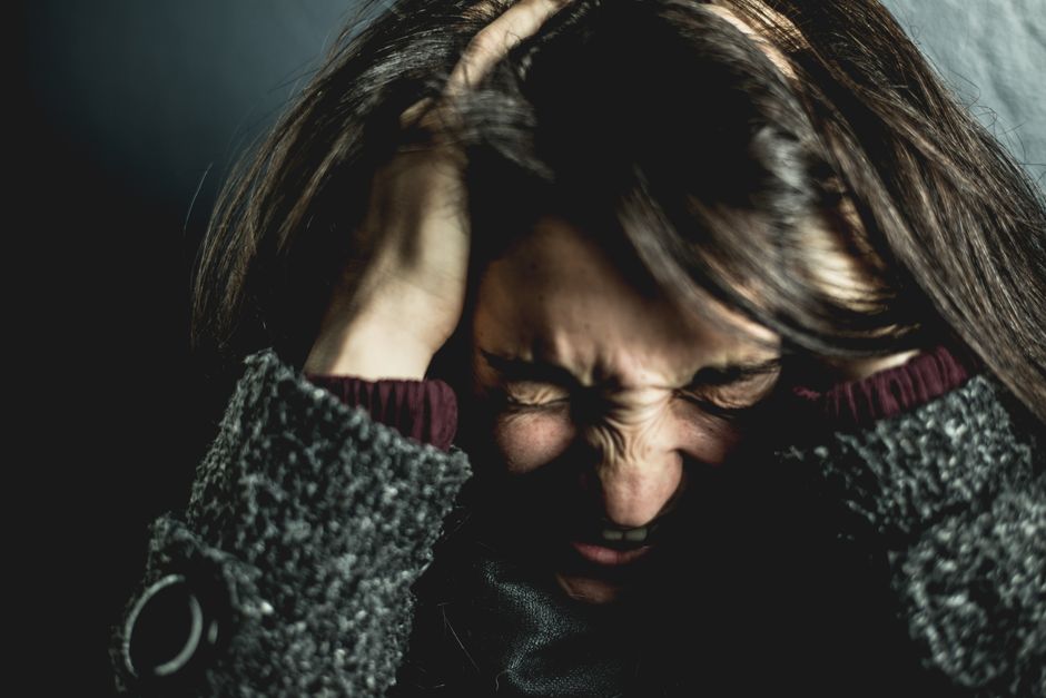 Pessoa com expressão de estresse ou frustração, segurando a cabeça com as mãos em um momento de angústia emocional.