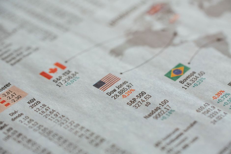 Imagem de uma página de jornal financeiro com destaque para índices de bolsas de valores e indicadores econômicos, ilustrando temas de mercado e economia internacional.