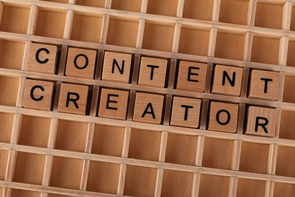 Imagem de peças de madeira formando uma grade, com blocos de letras que juntas escrevem 'Content Creator', representando criatividade e produção de conteúdo digital.