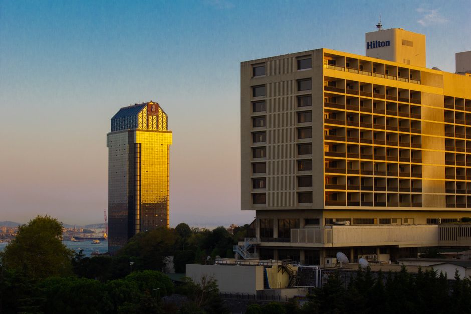 Imagem de edifícios comerciais ao pôr do sol, representando o tema de negócios e urbanismo.