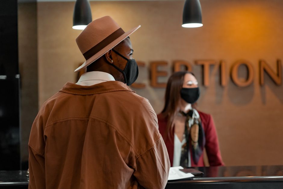 Homem aguardando atendimento na recepção de um espaço de coworking ou escritório moderno, com iluminação suave e ambiente acolhedor.