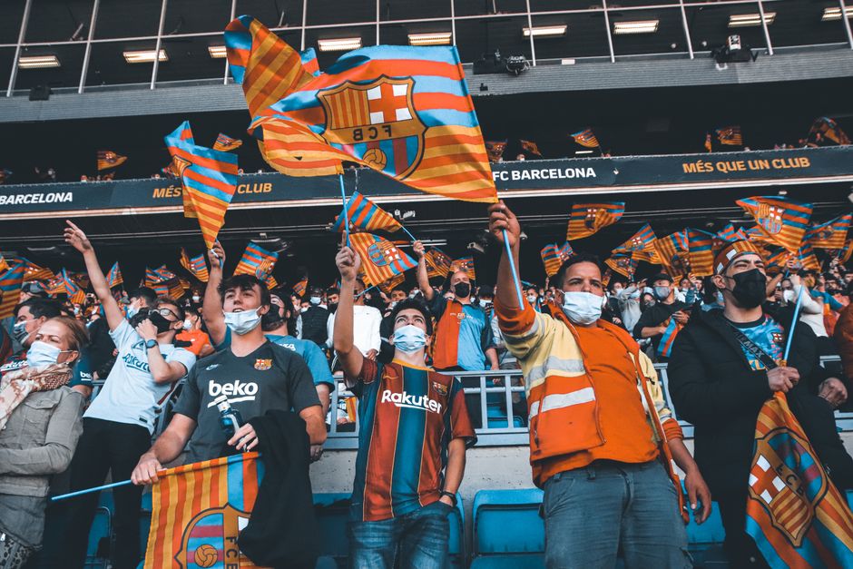 Torcida de torcedor do FC Barcelona comemorando em estádio com bandeiras da equipe, promovendo entusiasmo e paixão pelo futebol