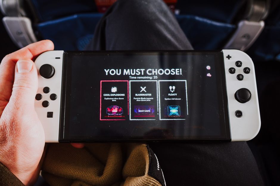 Pessoa jogando um jogo em um console portátil em um ambiente de viagem ou lazer.