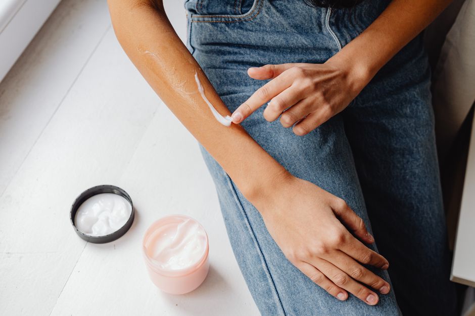 Pessoa aplicando creme na pele como rotina de cuidados pessoais ou skincare.