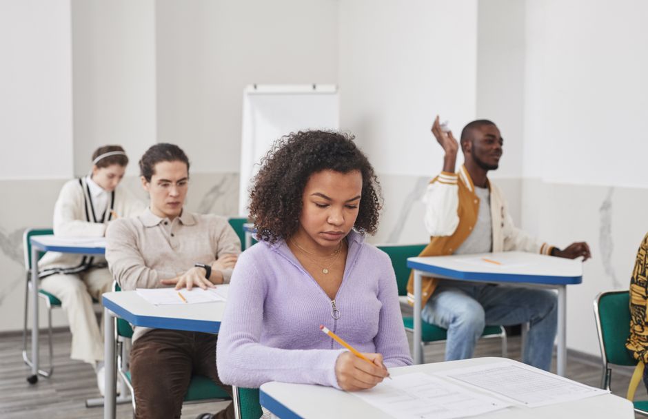 Mulher estudando em sala de aula, concentrada em uma prova ou atividade de aprendizagem.