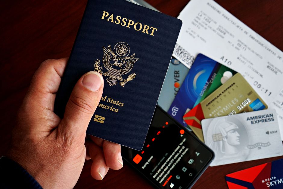 Pessoa segurando um passaporte com cartões de embarque e cartões de crédito, simbolizando preparação para viagem internacional e questões financeiras relacionadas ao deslocamento global.