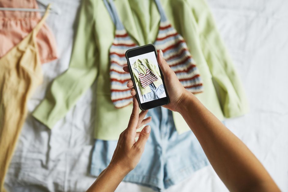 Pessoa tirando uma foto de roupas coloridas espalhadas sobre uma superfície, destacando a moda e o estilo casual.