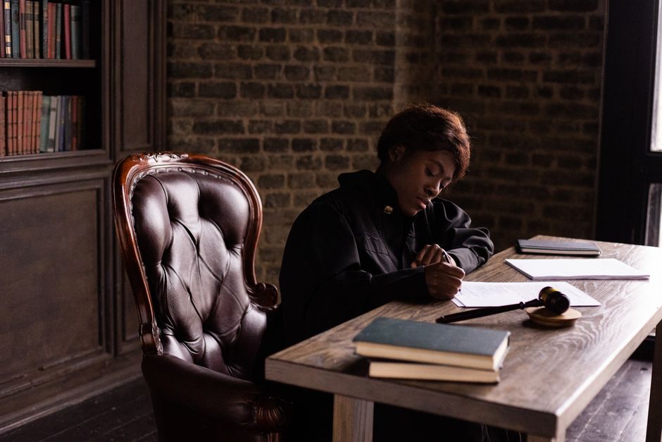 Mulher concentrada estudando ou revisando documentos em um ambiente de escritório, com uma vibe de trabalho sério e ambiente interno confortável.