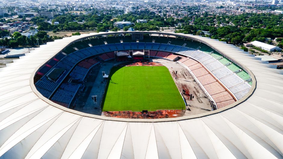 Imagem de um estádio de futebol visto do alto, destacando a estrutura e o campo em uso ou preparo para uma partida ou evento esportivo.