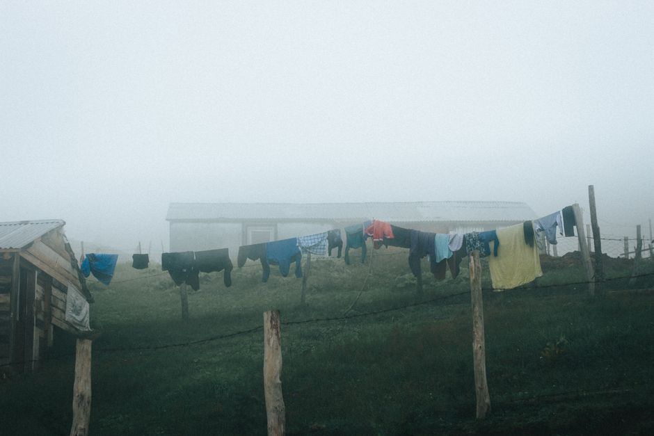 Imagem que retrata a rotina simples em uma área rural, com roupas penduradas para secar ao ar livre em uma manhã de névoa.