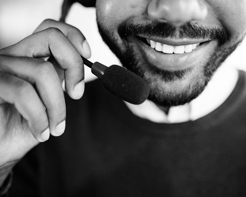 Homem sorridente usando um headset com microfone, representando atendimento ao cliente ou suporte técnico.