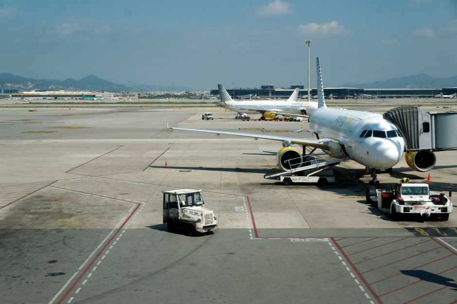 Imagem de um terminal de aeroporto com aviões em solo e equipamentos de apoio à aeronave.