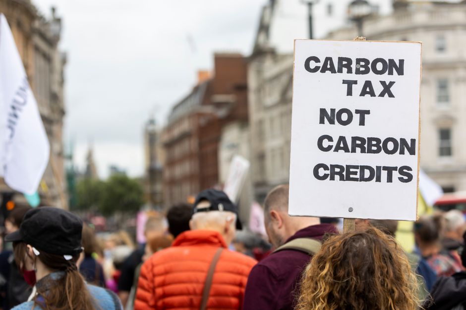 Manifestantes participando de uma passeata ambiental discutindo a taxação de carbono e créditos de carbono.