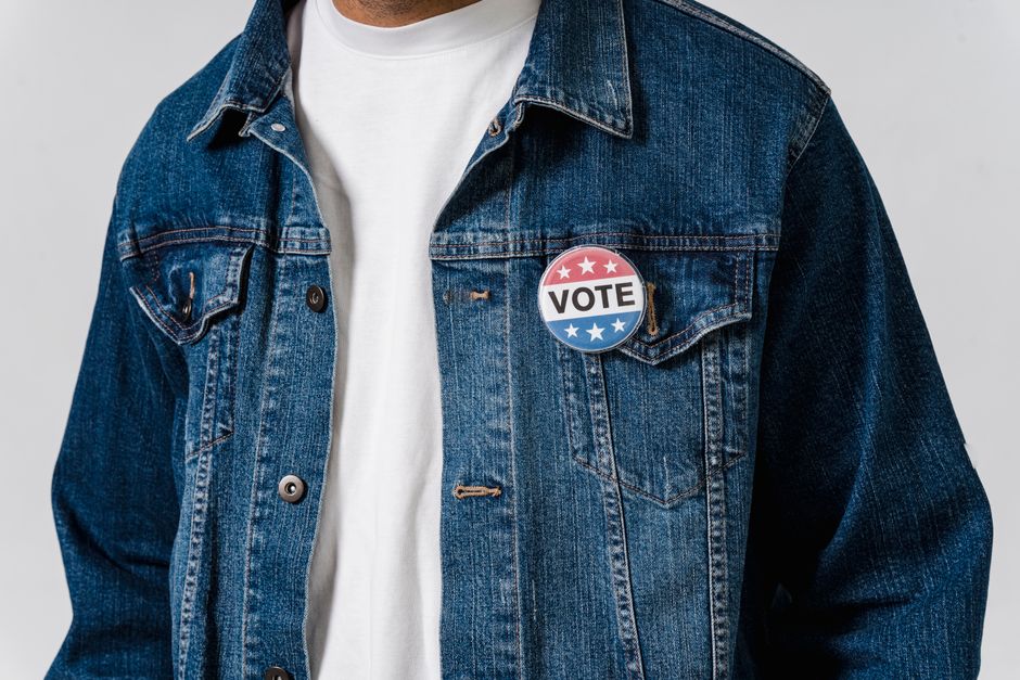 Pessoa usando jaqueta jeans com uma botton de votação, simbolizando participação cívica e engajamento político.