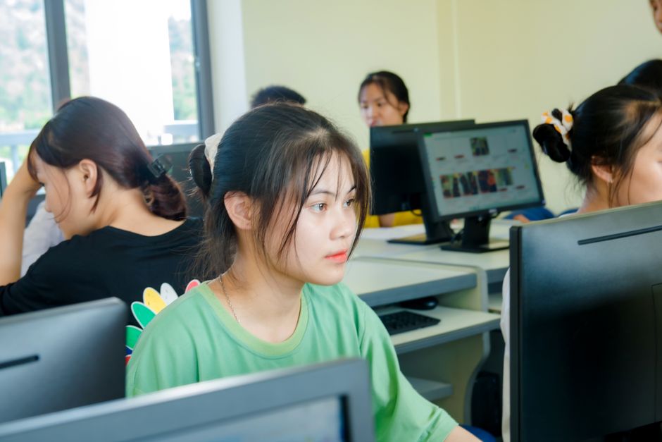 Juventudes em sala de aula utilizando computadores, representando educação tecnológica e aprendizagem digital.
