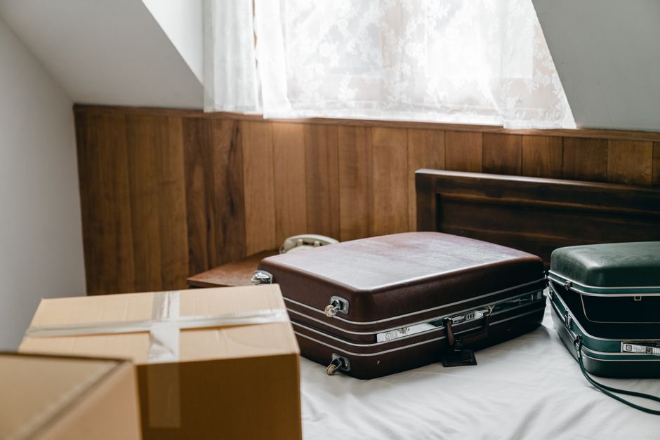Imagem de malas de viagem e caixas de papelão em um ambiente doméstico, sugerindo planejamento e preparação para uma viagem ou mudança.