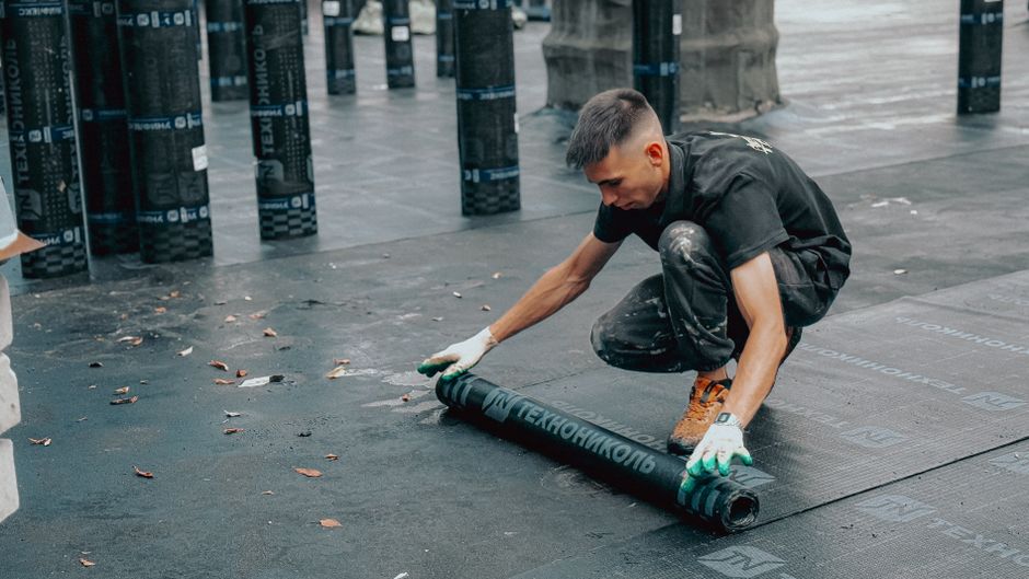 Homem instalando ou ajustando uma nova camada de material de isolamento em um ambiente de construção ou renovação de piso.