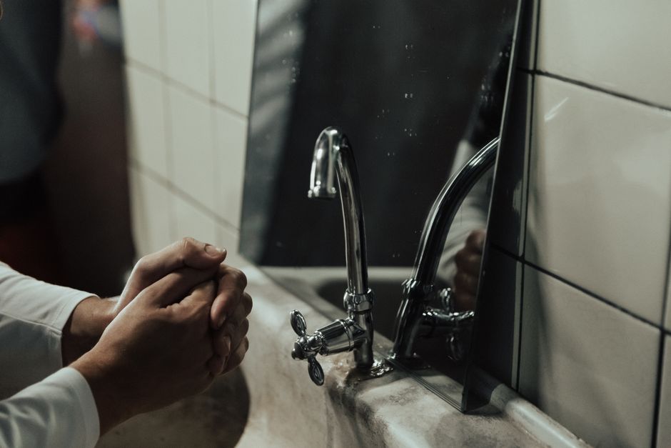 Imagem de uma pessoa lavando as mãos na pia de um banheiro, representando higiene pessoal e segurança sanitária.