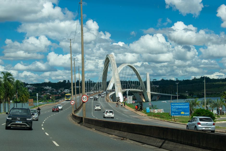 Imagem de uma ponte moderna sobre um rio, com veículos em trânsito sob um céu nublado, ideal para ilustrar temas relacionados a infraestrutura urbana ou transporte.