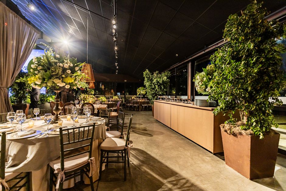 Espaço para eventos ou jantar elegante decorado com plantas e iluminação suave, ideal para festas ou reuniões especiais.