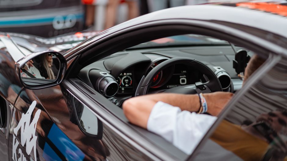 Imagem de um carro de corrida sendo guiado por um motorista, destacando a adrenalina e a velocidade no esporte automobilístico.