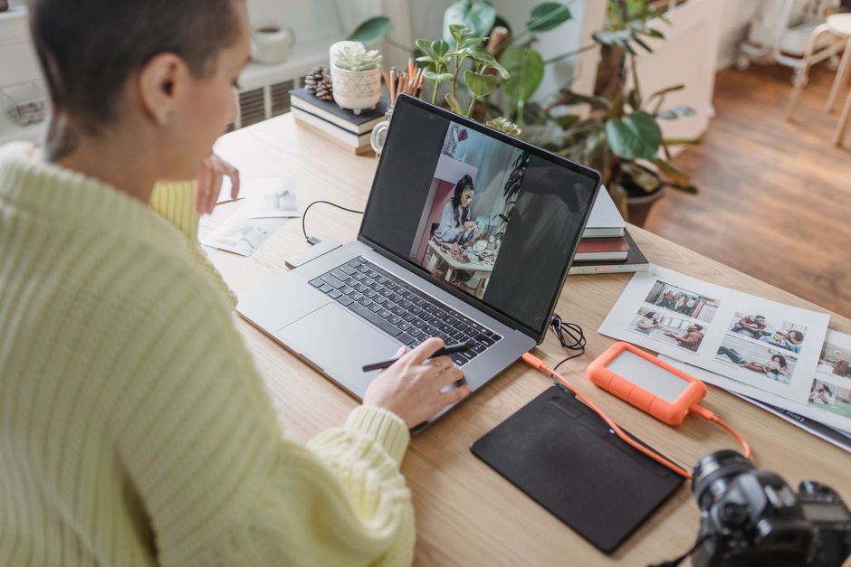Mulher participando de uma reunião virtual em um ambiente de home office, com materiais de trabalho e plantas ao redor.