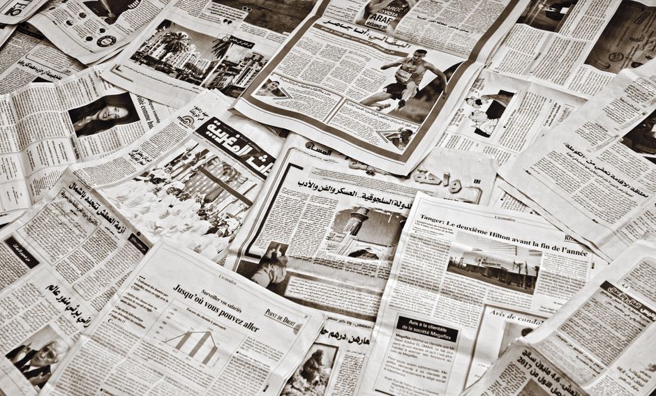 Imagem de várias páginas de jornais espalhadas, simbolizando o contexto de informações, notícias e comunicação impressa.