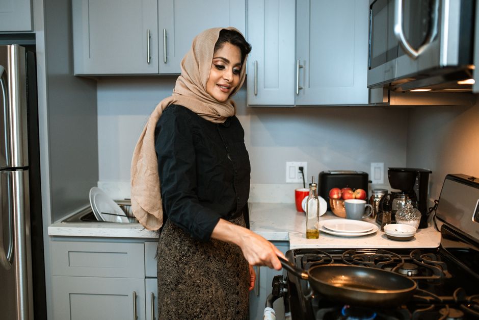 Mulher preparando comida na cozinha, simbolizando rotina doméstica e culinária.