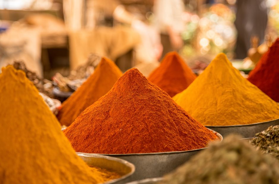 imagem de diversas especiarias em pó dispostas em conchas, destacando a variedade de cores vibrantes, típicas de mercado de temperos naturais